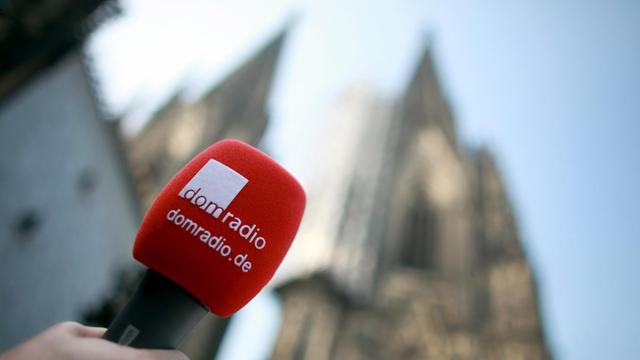 Ein Mikrofon des Radiosenders domradio vor der Kulisse des Kölner Doms