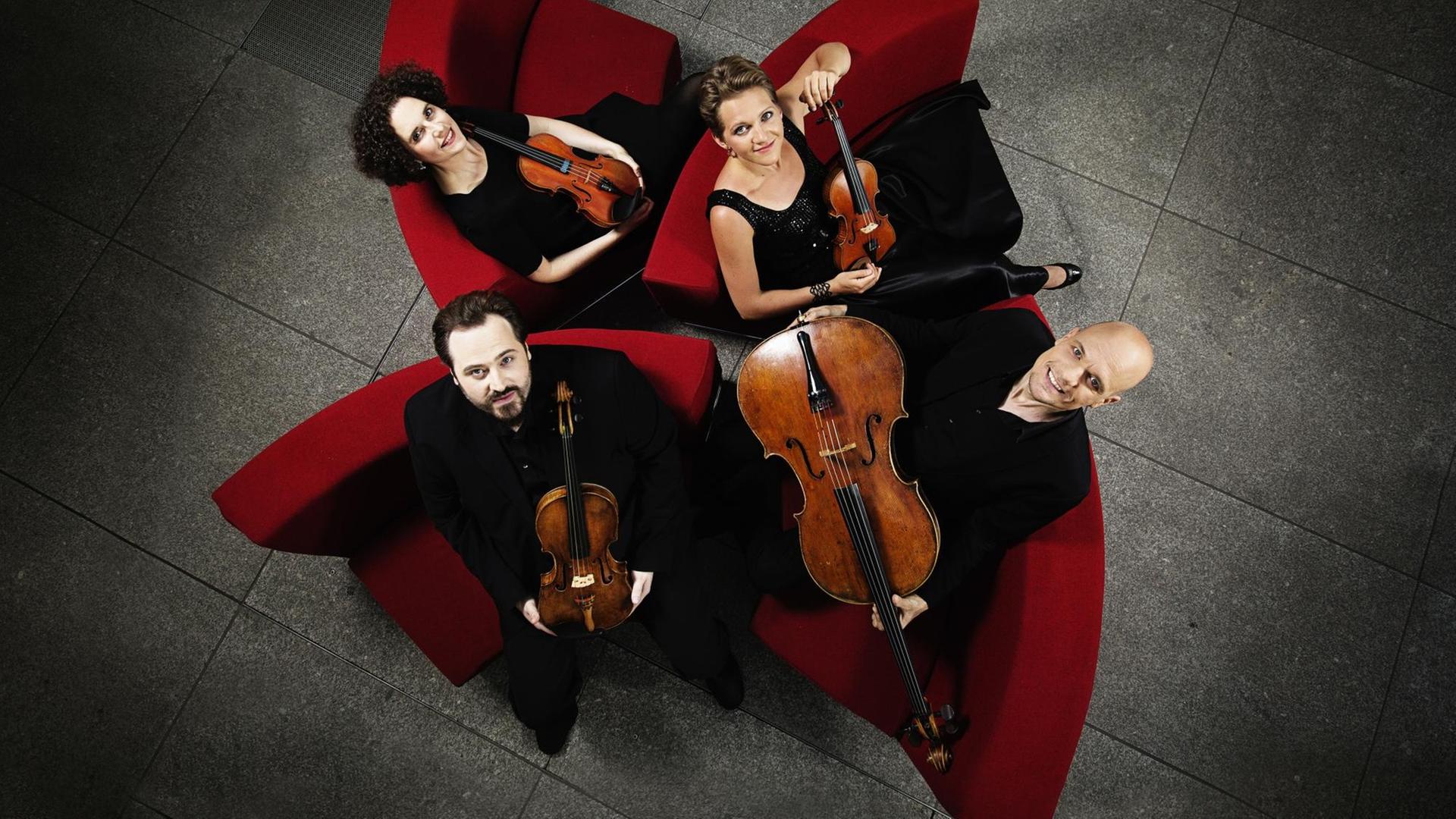 Die Musiker des Artemis Quartett sitzen mit ihren Instrumenten roten Sesseln und blicken nach oben, Bild aufgenommen in Vogelperspektive Die Musiker des Artemis Quartett sitzen mit ihren Instrumenten roten Sesseln und blicken nach oben, Bild aufgenommen in Vogelperspektive