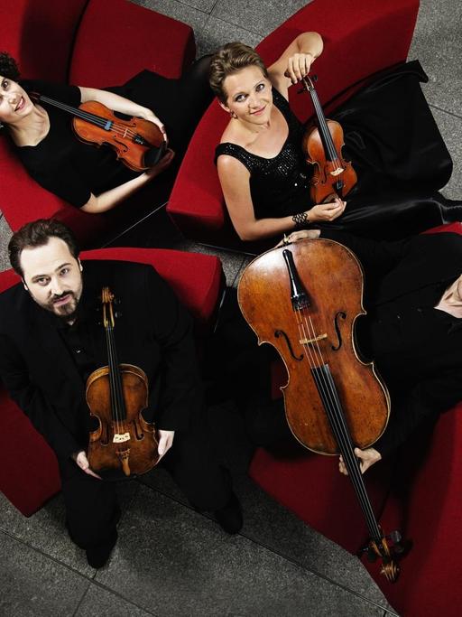 Die Musiker des Artemis Quartett sitzen mit ihren Instrumenten roten Sesseln und blicken nach oben, Bild aufgenommen in Vogelperspektive