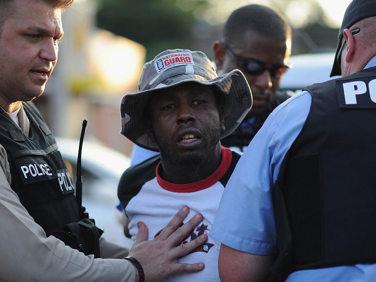 In der US-Kleinstadt Ferguson nimmt die die Polizei einen schwarzen Demonstranten fest.