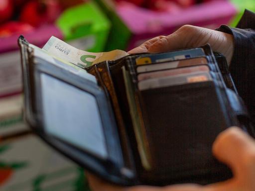 Eine Frau holt eine 5-Euro-Banknote aus ihrem Portemonnaie