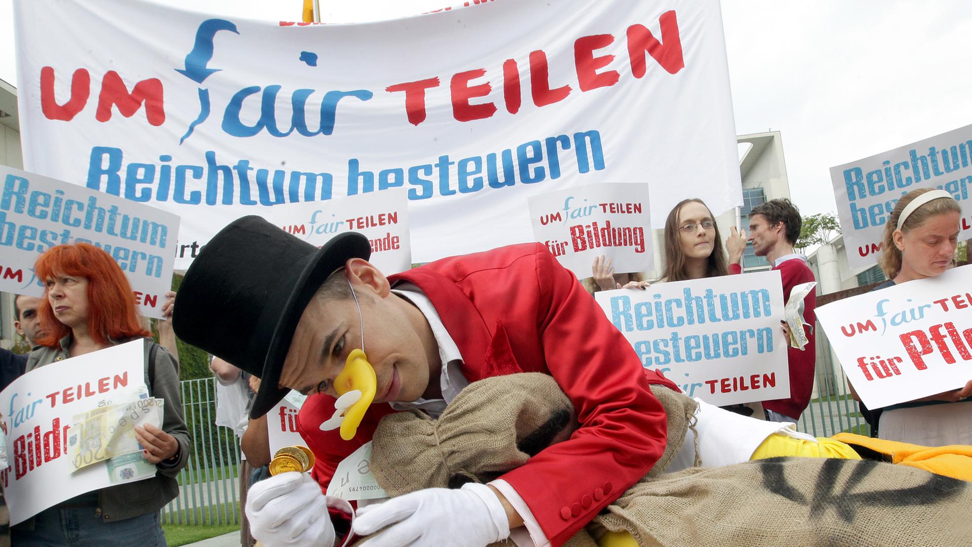 "Umfairteilen": Menschen demonstrieren am Freitag (03.08.2012) vor dem Bundeskanzleramt in Berlin für eine stärkere Besteuerung von Reichtum. "Umfairteilen": Menschen demonstrieren am Freitag (03.08.2012) vor dem Bundeskanzleramt in Berlin für eine stärkere Besteuerung von Reichtum.