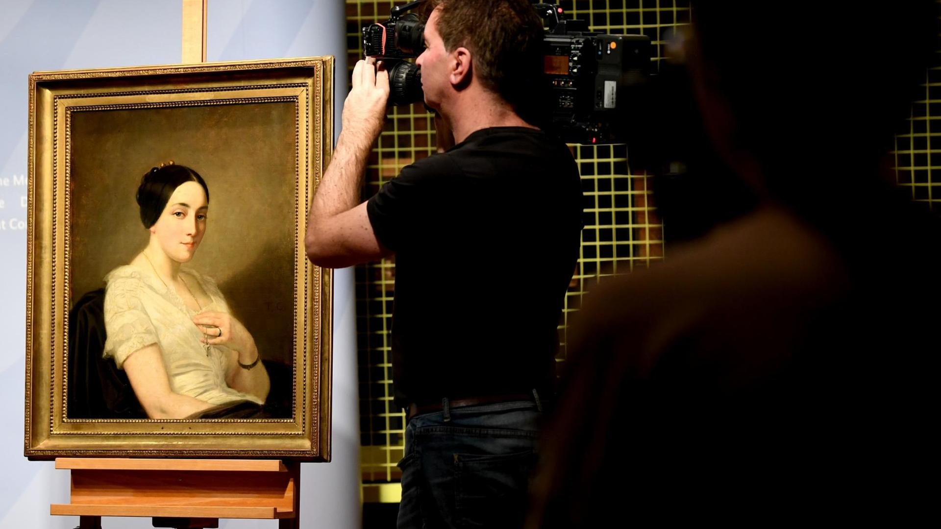 Journalisten filmen das Bild "Portrait einer sitzenden jungen Frau / Portrait de jeune femme assise" des Künstlers Thomas Couture. Das Gemälde aus dem Kunstfund Gurlitt, wurde NS-Raubkunst identifiziert und an die Nachkommen zurückgegeben.