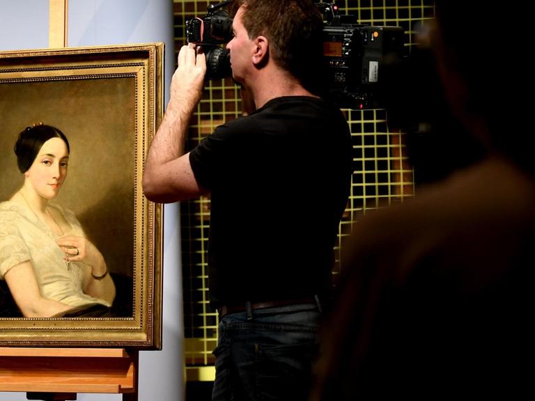 Journalisten filmen das Bild "Portrait einer sitzenden jungen Frau / Portrait de jeune femme assise" des Künstlers Thomas Couture. Das Gemälde aus dem Kunstfund Gurlitt, wurde NS-Raubkunst identifiziert und an die Nachkommen zurückgegeben.