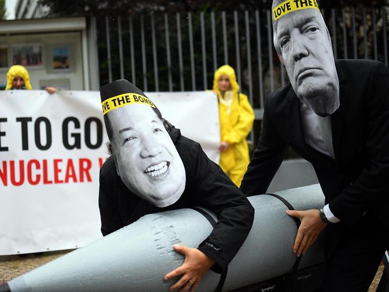 Aktivisten der Internationalen Kampagne zur Abschaffung von Atomwaffen (ICAN) protestieren vor der nordkoreanischen Botschaft in Berlin mit Masken des nordkoreanischen Machthabers Jong-un (l) und des US-Präsidenten Trump gegen den Konflikt zwischen Nordkorea und den USA.