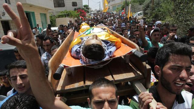 Teilnehmer des Trauerzugs tragen eine Bahre mit dem Leichnam des erschossenen 14-jährigen Mohammed Dudin.