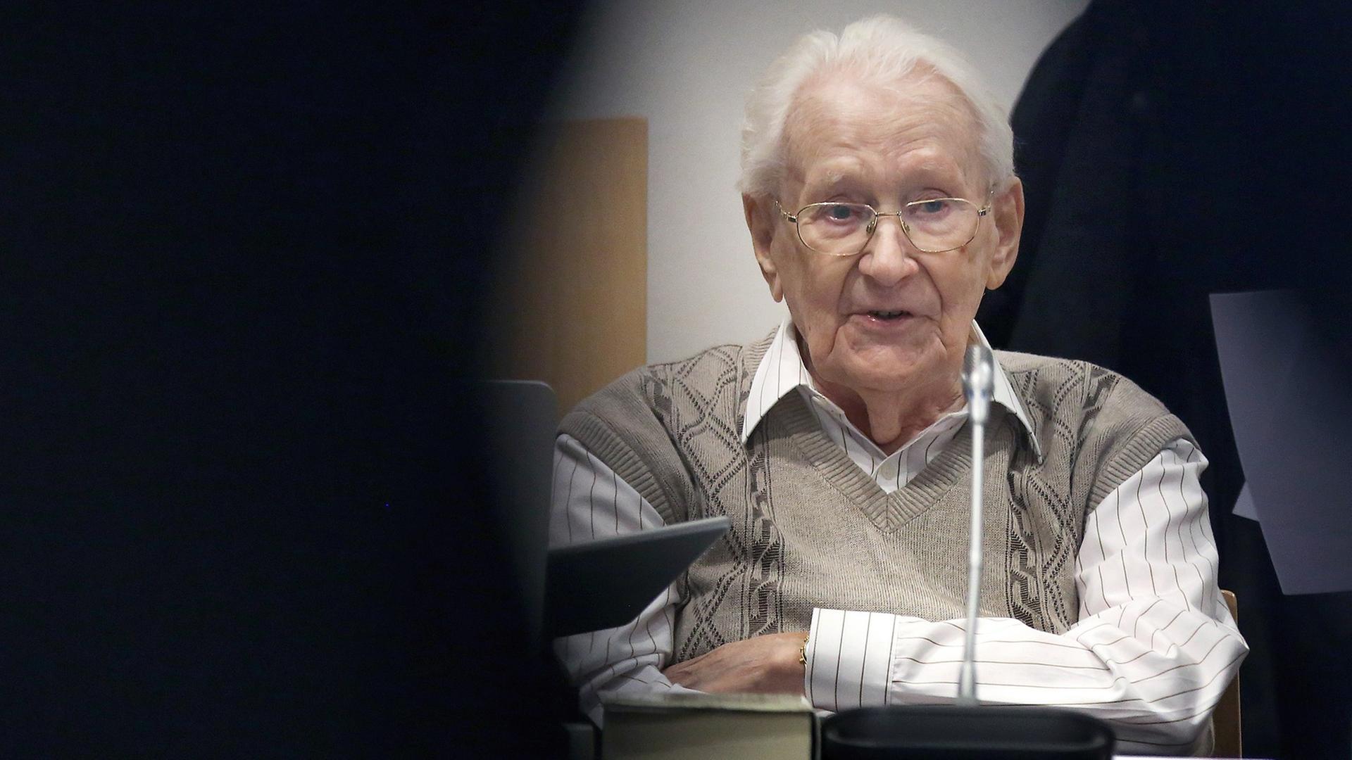 Oskar Gröning sitzt mit verschränkten Armen auf der Anklagebank. Oskar Gröning sitzt mit verschränkten Armen auf der Anklagebank.