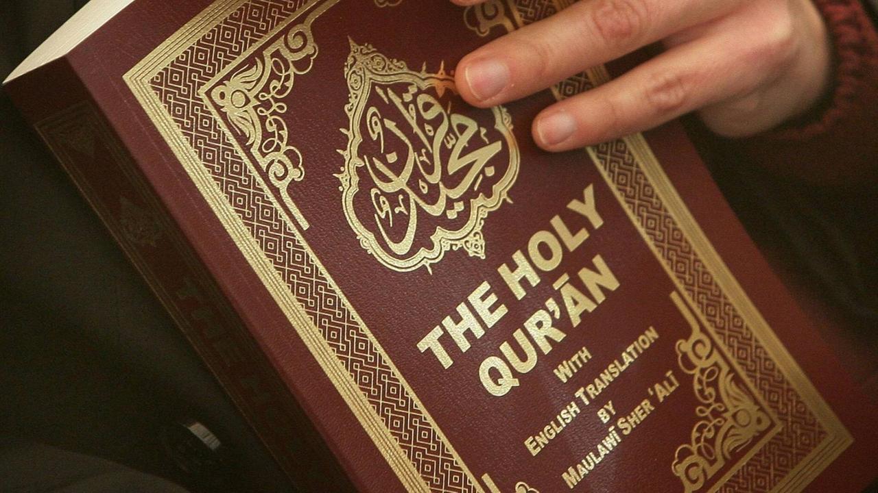 Eine Frau hält einen Koran in englischer Übersetzung Eine Frau hält einen Koran in englischer Übersetzung