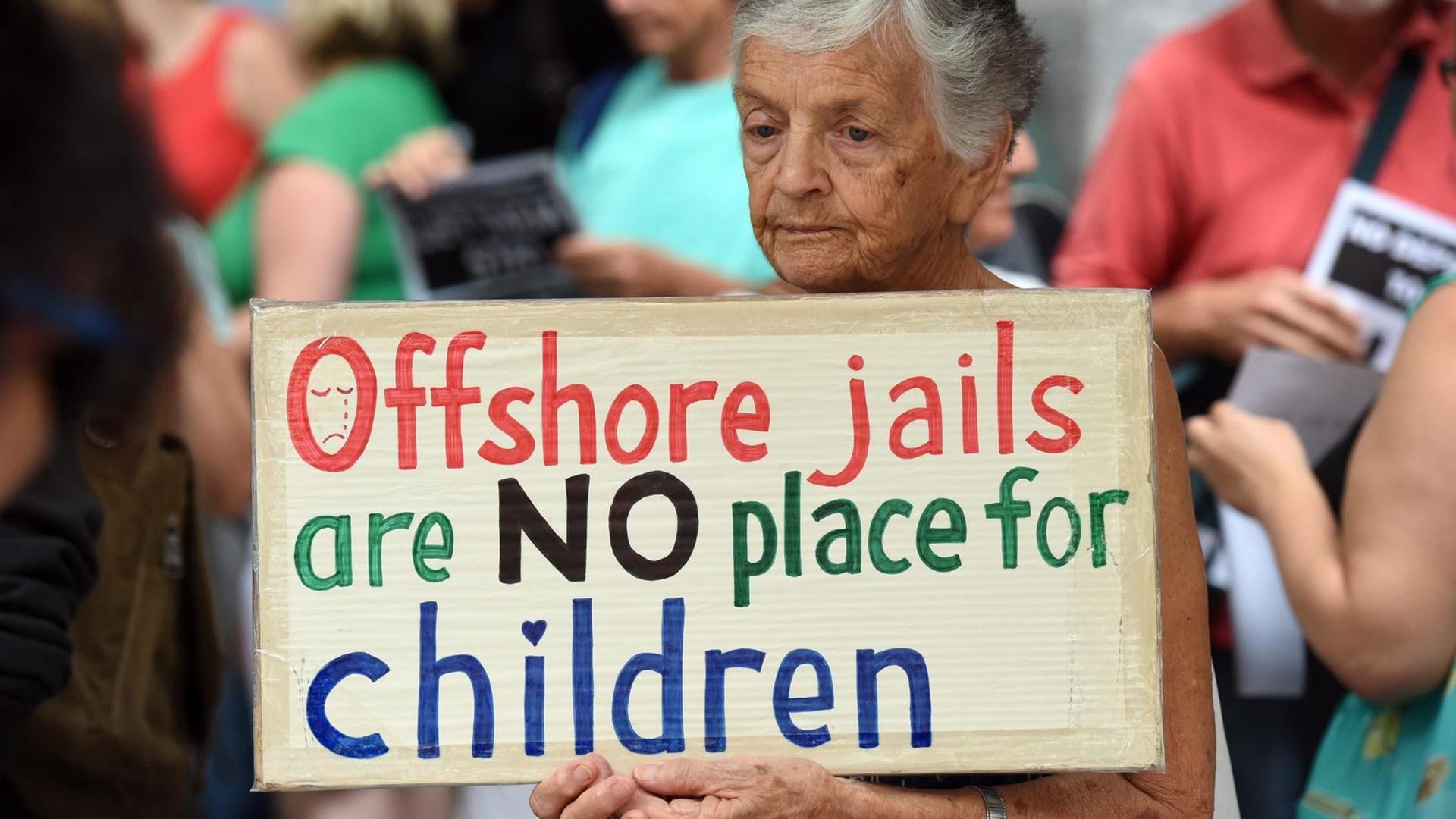 Eine Frau bei einem Prostest in Brisbane/Australien. Sie hält ein Schild mit der Aufschrift: "Übersee-Gefängnisse sind kein Ort für Kinder" und protestiert damit gegen die Flüchtlingslager der australischen Regierung im Pazifik. Eine Frau bei einem Prostest in Brisbane/Australien. Sie hält ein Schild mit der Aufschrift: "Übersee-Gefängnisse sind kein Ort für Kinder" und protestiert damit gegen die Flüchtlingslager der australischen Regierung im Pazifik.