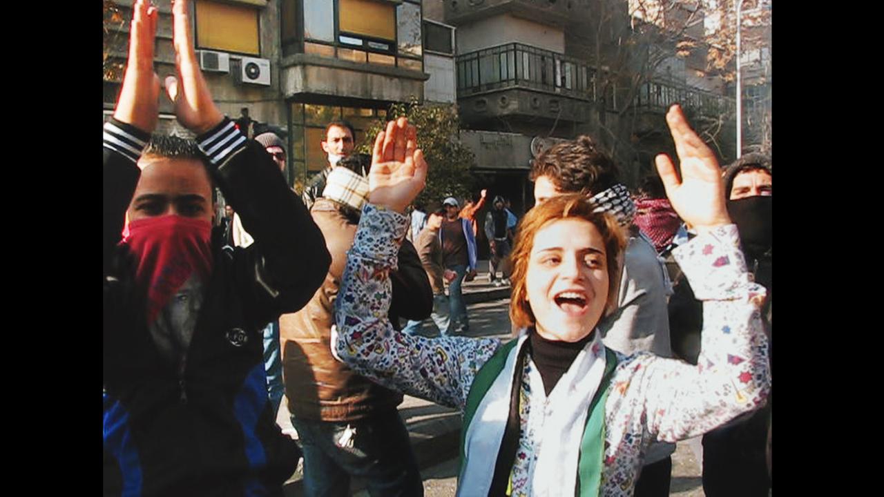 Ausschnitt aus dem Dokumentatfilm "The War Show": Junge Syrer jubeln auf einer Demonstration - Teile der Gesichter von einigen sind mit Tüchern verdeckt