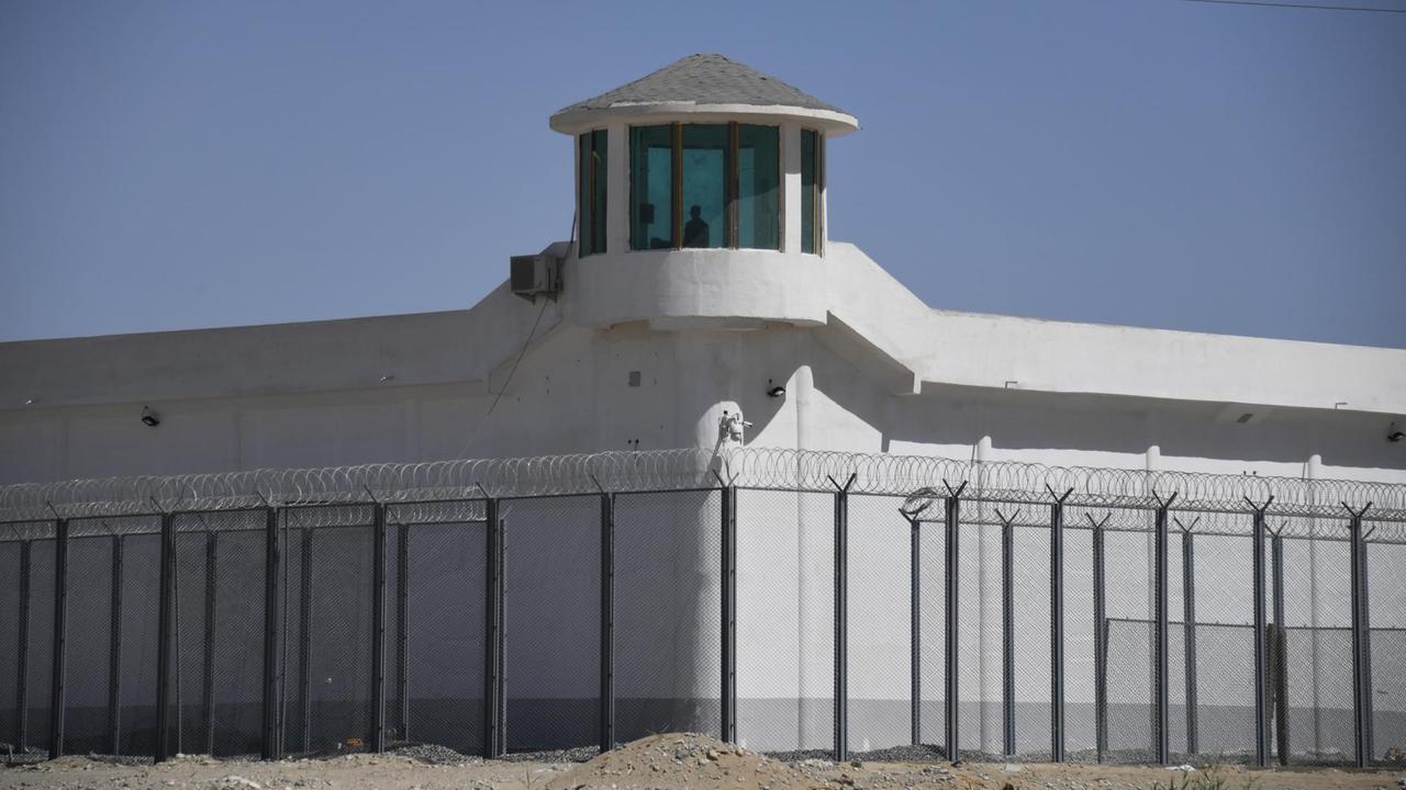 Ein Wachturm einem mit hohem Zaun und Stacheldraht gesicherten, nicht einsichtigen Komplex., vermutlich ein Lager in der Nähe der Stadt Hotan, in der Region Xinjiang im Nordwesten Chinas. Ein Wachturm einem mit hohem Zaun und Stacheldraht gesicherten, nicht einsichtigen Komplex., vermutlich ein Lager in der Nähe der Stadt Hotan, in der Region Xinjiang im Nordwesten Chinas.
