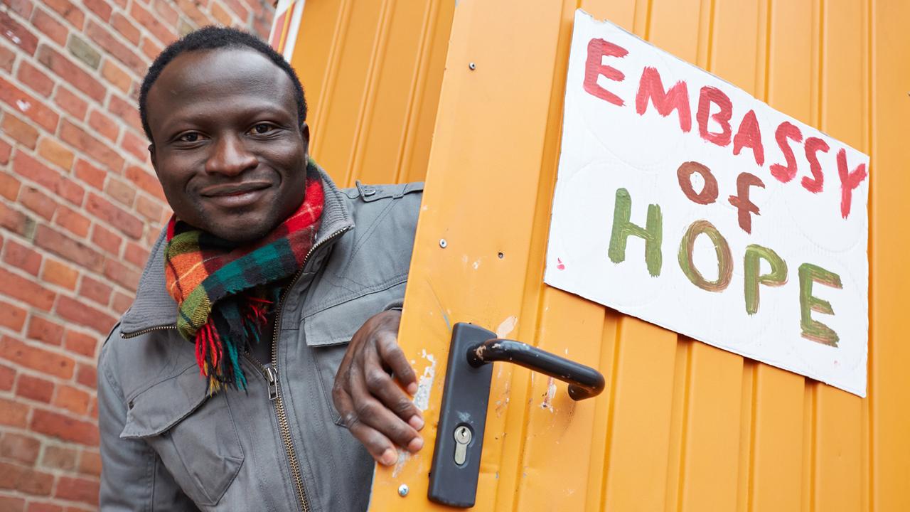 Der Ghanaer Andreas Listowell als Vertreter der "Lampedusa-Flüchtlinge" posiert in Hamburg an der Tür eines Bauwagens mit der Aufschrift "Embassy of Hope". 