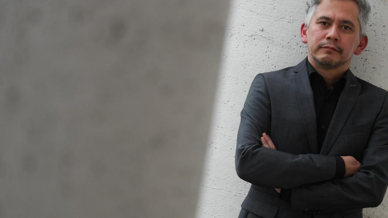 Der Autor André Kubiczek lehnt an einer hellgrauen Wand. Der Autor André Kubiczek lehnt an einer hellgrauen Wand.