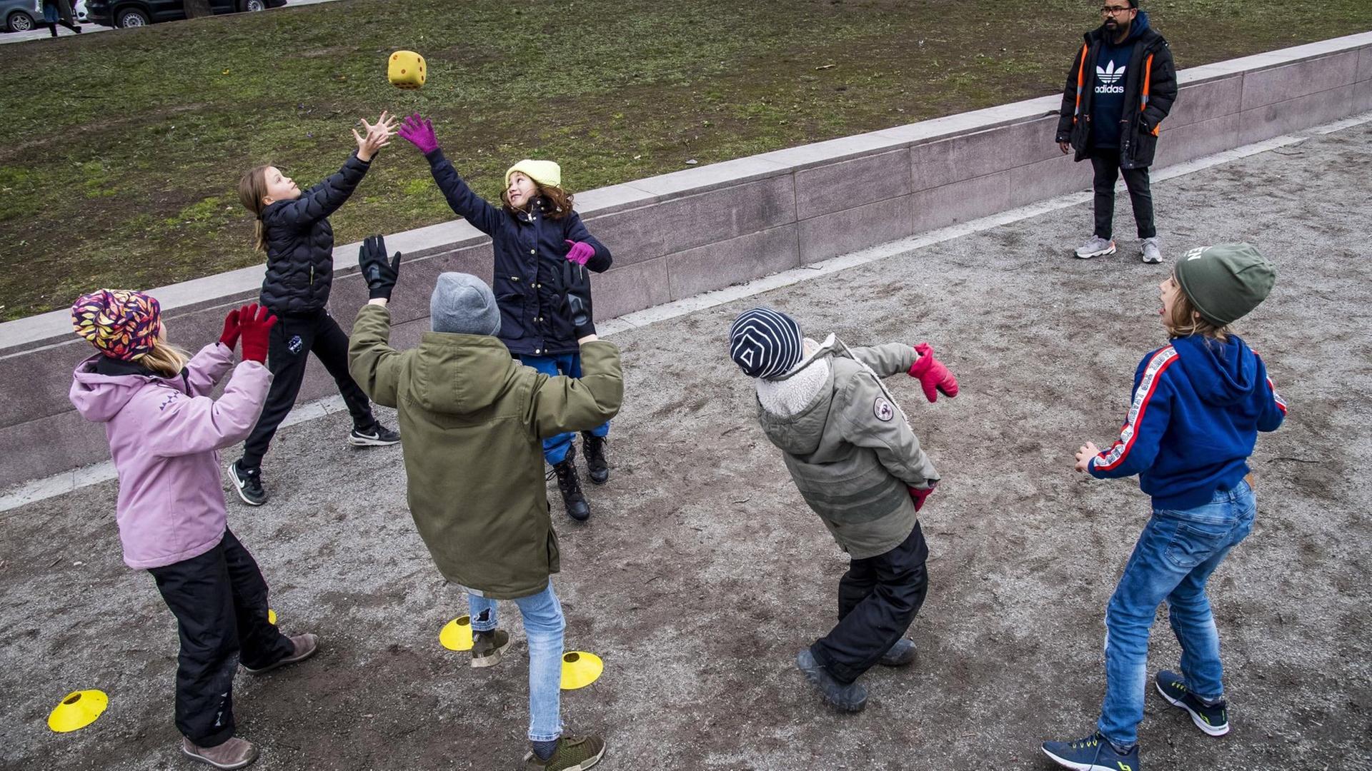 Mehrere Kinder spielen auf einem Spieplatz in Schweden zusammen mit einem Ball