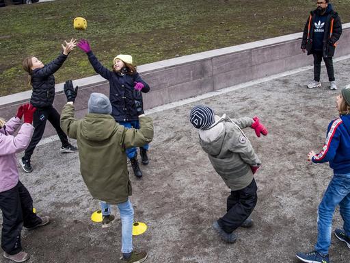 Mehrere Kinder spielen auf einem Spieplatz in Schweden zusammen mit einem Ball