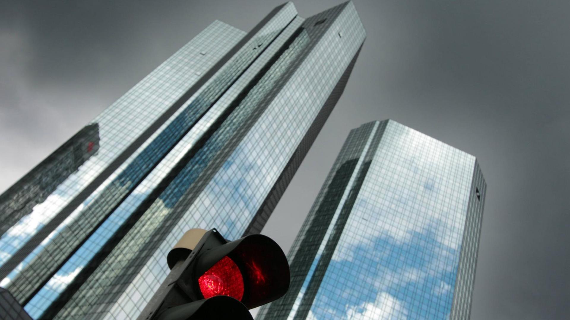 Eine rote Verkehrsampel vor der Zentrale des Unternehmens mit schwarzen Regenwolken im Bankenviertel in Frankfurt am Main. Eine rote Verkehrsampel vor der Zentrale des Unternehmens mit schwarzen Regenwolken im Bankenviertel in Frankfurt am Main.