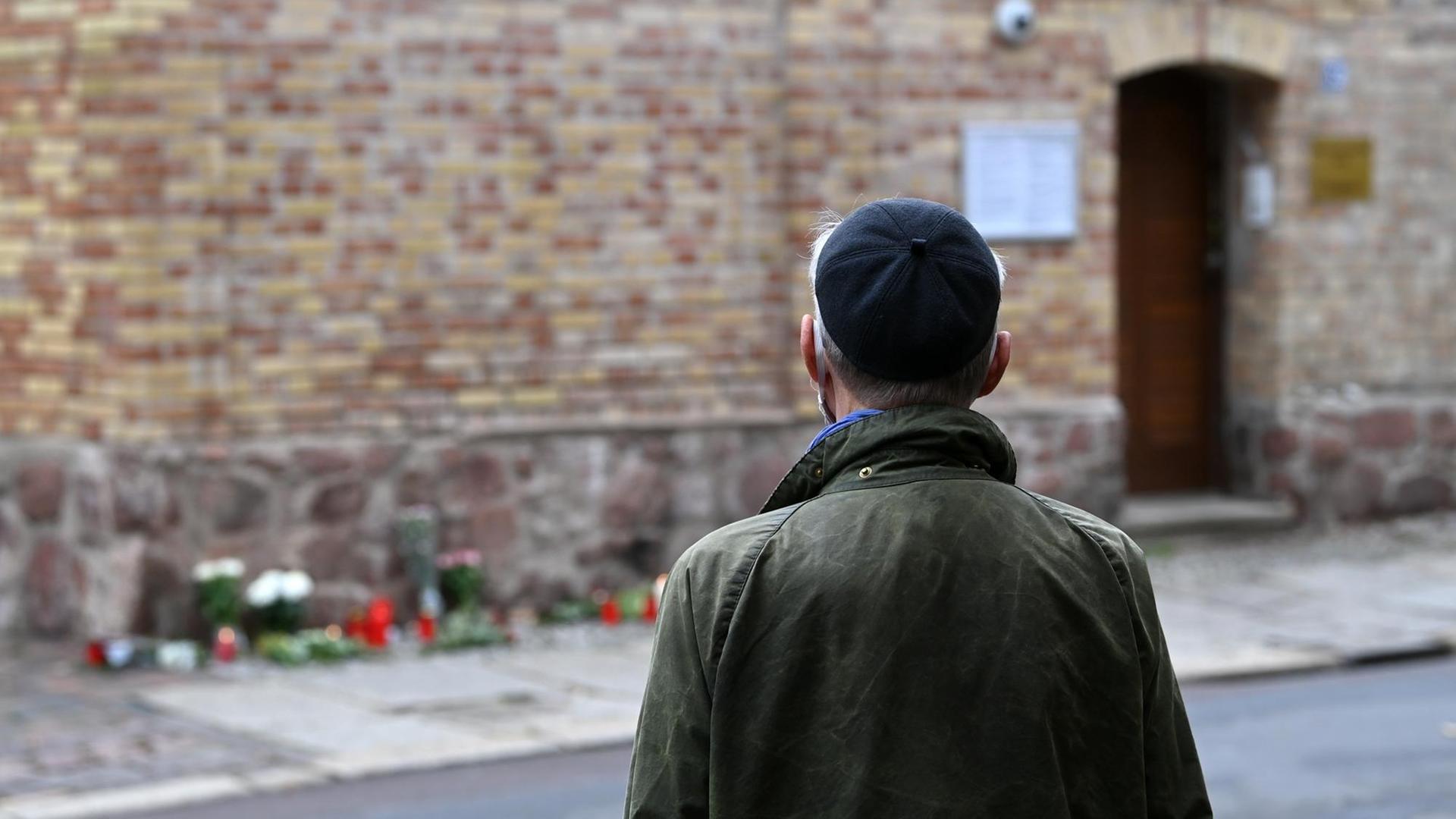09.10.2020, Sachsen-Anhalt, Halle (Saale): Ein Mann steht während der Schweigeminute 12:01 Uhr zum Gedenken der Opfer des Terroranschlags von Halle/Saale vor der Synagoge. Zu dieser Zeit fielen die ersten Schüsse auf das jüdische Gotteshaus. Ein Jahr nach dem rechtsterroristischen Anschlag am höchsten jüdischen Feiertag Jom Kippur in Halle wird mit Veranstaltungen und Gebeten der Opfer gedacht. Am 09. Oktober 2019 hatte ein schwer bewaffneter Rechtsextremist versucht, die Synagoge zu stürmen und ein Massaker unter 52 Besuchern anzurichten. Als ihm das nicht gelang, erschoss er eine Passantin und in einem Dönerimbiss einen jungen Mann. Foto: Hendrik Schmidt/dpa-Zentralbild/dpa | Verwendung weltweit 09.10.2020, Sachsen-Anhalt, Halle (Saale): Ein Mann steht während der Schweigeminute 12:01 Uhr zum Gedenken der Opfer des Terroranschlags von Halle/Saale vor der Synagoge. Zu dieser Zeit fielen die ersten Schüsse auf das jüdische Gotteshaus. Ein Jahr nach dem rechtsterroristischen Anschlag am höchsten jüdischen Feiertag Jom Kippur in Halle wird mit Veranstaltungen und Gebeten der Opfer gedacht. Am 09. Oktober 2019 hatte ein schwer bewaffneter Rechtsextremist versucht, die Synagoge zu stürmen und ein Massaker unter 52 Besuchern anzurichten. Als ihm das nicht gelang, erschoss er eine Passantin und in einem Dönerimbiss einen jungen Mann. Foto: Hendrik Schmidt/dpa-Zentralbild/dpa | Verwendung weltweit