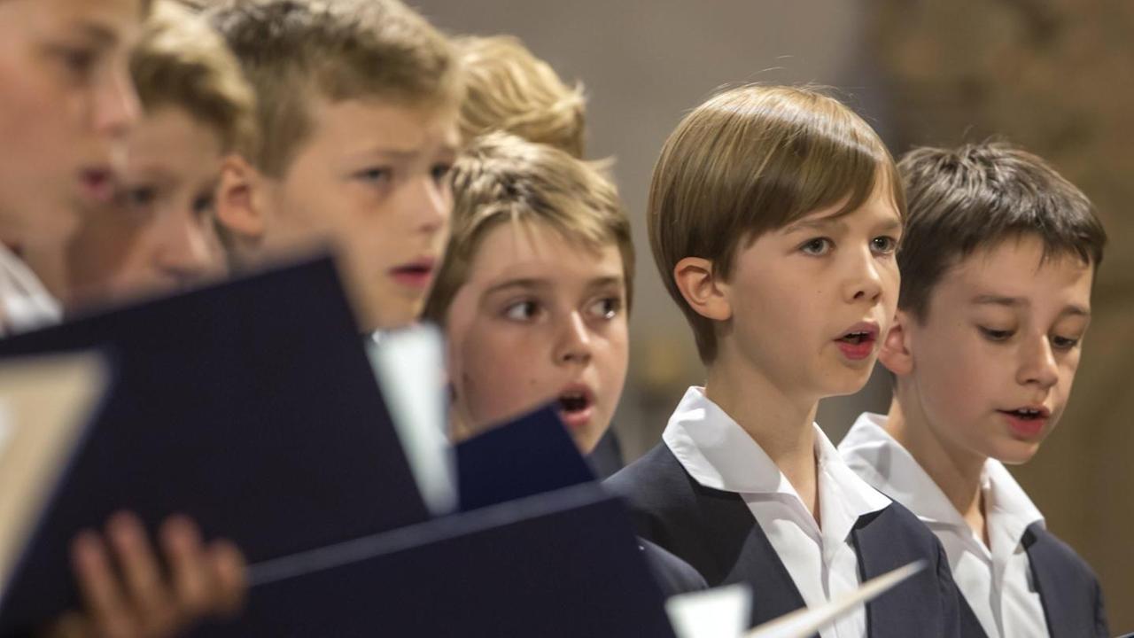 Jungs stehen mit Chormappen und Chorkleidung nebeneinander und singen. Jungs stehen mit Chormappen und Chorkleidung nebeneinander und singen.