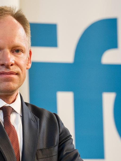 Der Präsident des ifo Instituts, Clemens Fuest, posiert vor einem Schild mit der Aufschrift "ifo".