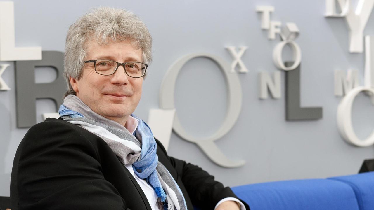Der Historiker Tillmann Bendikowski sitzend auf dem blauen Sofa. Der Historiker Tillmann Bendikowski sitzend auf dem blauen Sofa.