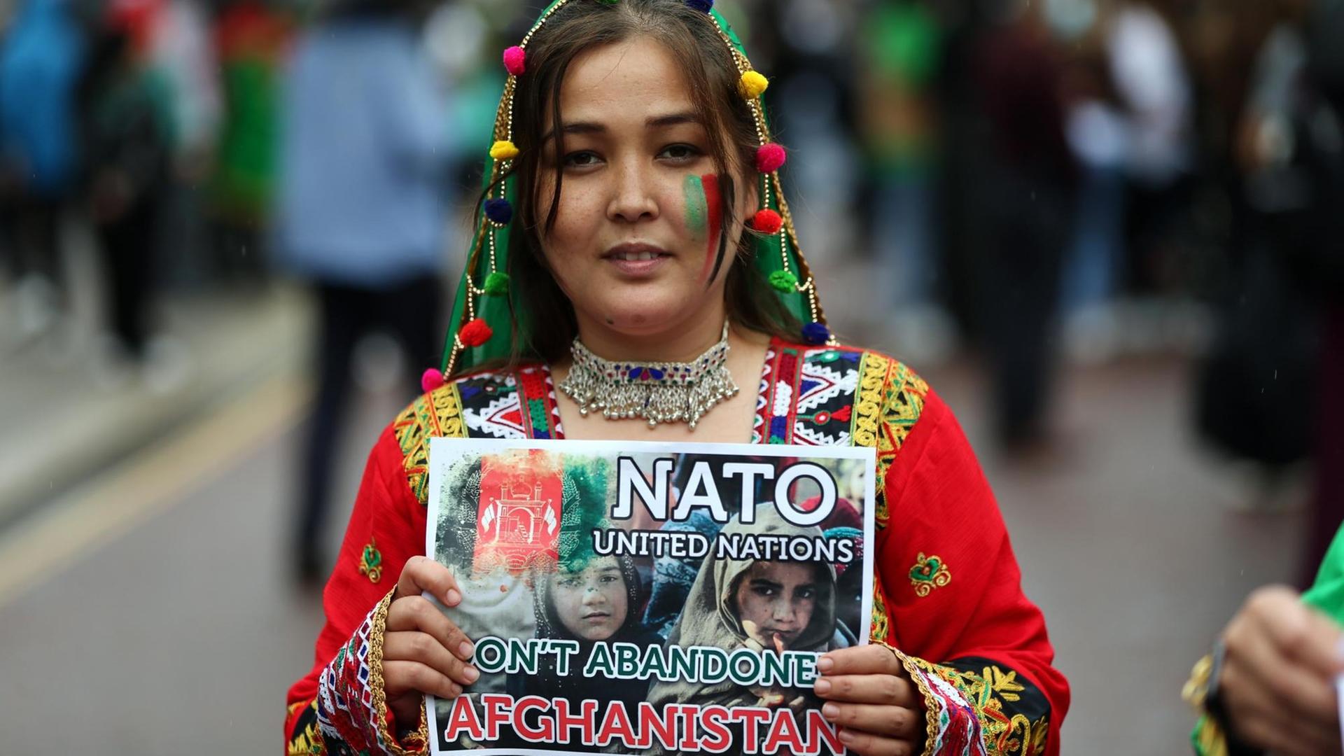 Eine Frau hält ein Schild hoch, auf dem sie die NATO zur Unterstützung für Afghanistan auffordert Eine Frau hält ein Schild hoch, auf dem sie die NATO zur Unterstützung für Afghanistan auffordert