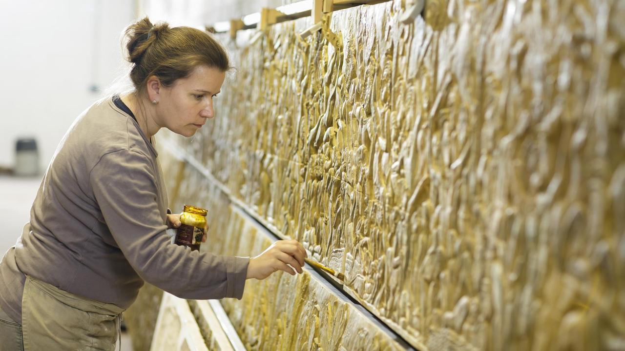 Eine Restauratorin arbeitet mit einem Pinsel an den Angkor Vat Reliefs. Eine Restauratorin arbeitet mit einem Pinsel an den Angkor Vat Reliefs.