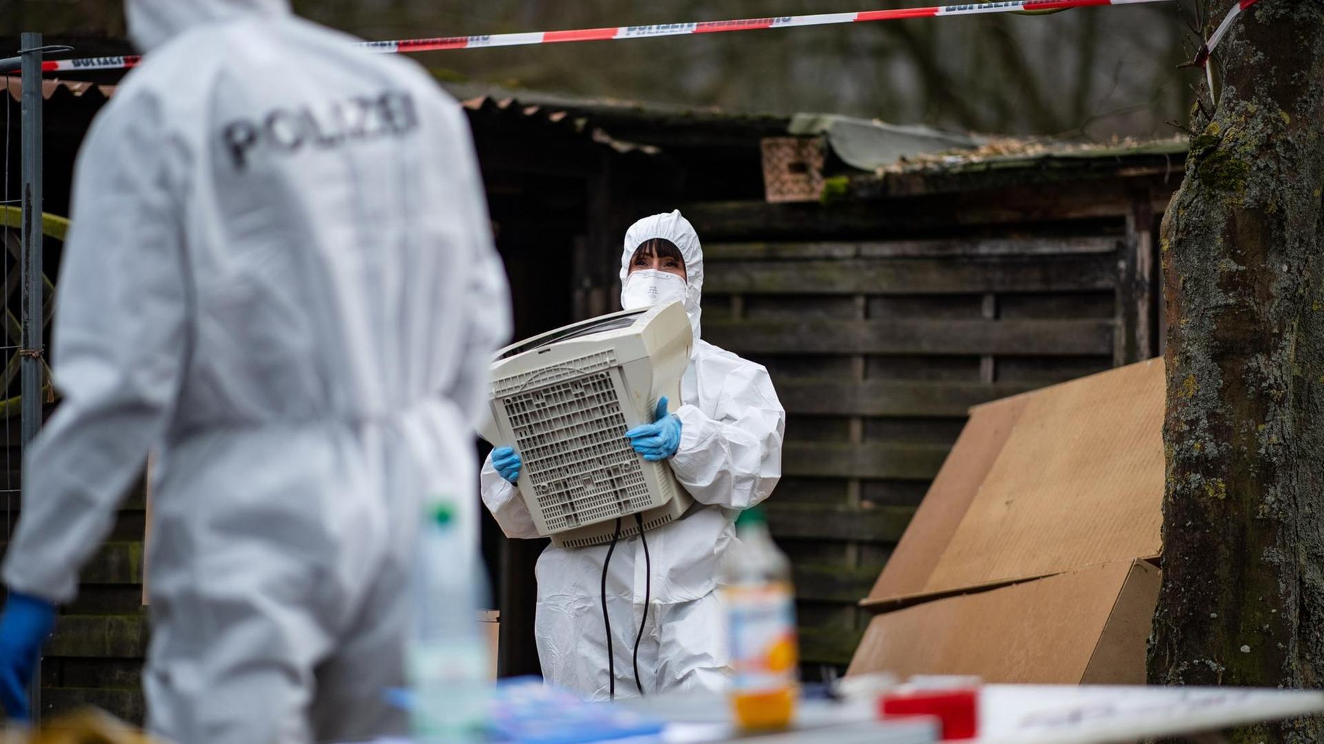 Eine Polizeibeamtin einer Spezialeinheit trägt einen sichergestellten Monitor aus der abgesperrten Parzelle des mutmaßlichen Täters auf dem Campingplatz Eichwald in Lügde. Eine Polizeibeamtin einer Spezialeinheit trägt einen sichergestellten Monitor aus der abgesperrten Parzelle des mutmaßlichen Täters auf dem Campingplatz Eichwald in Lügde.