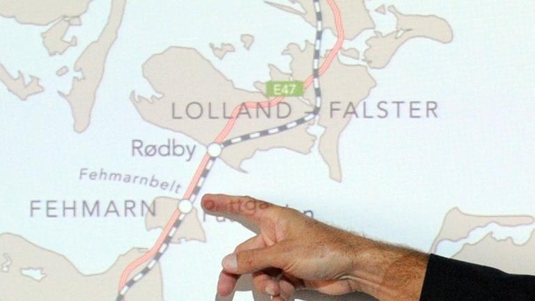 Eine Hand mit ausgestrecktem Finger zeigt auf einer Karte den geplanten Tunnelverlauf von der deutschen Insel Fehmarn zur dänischen Insel Lolland.
