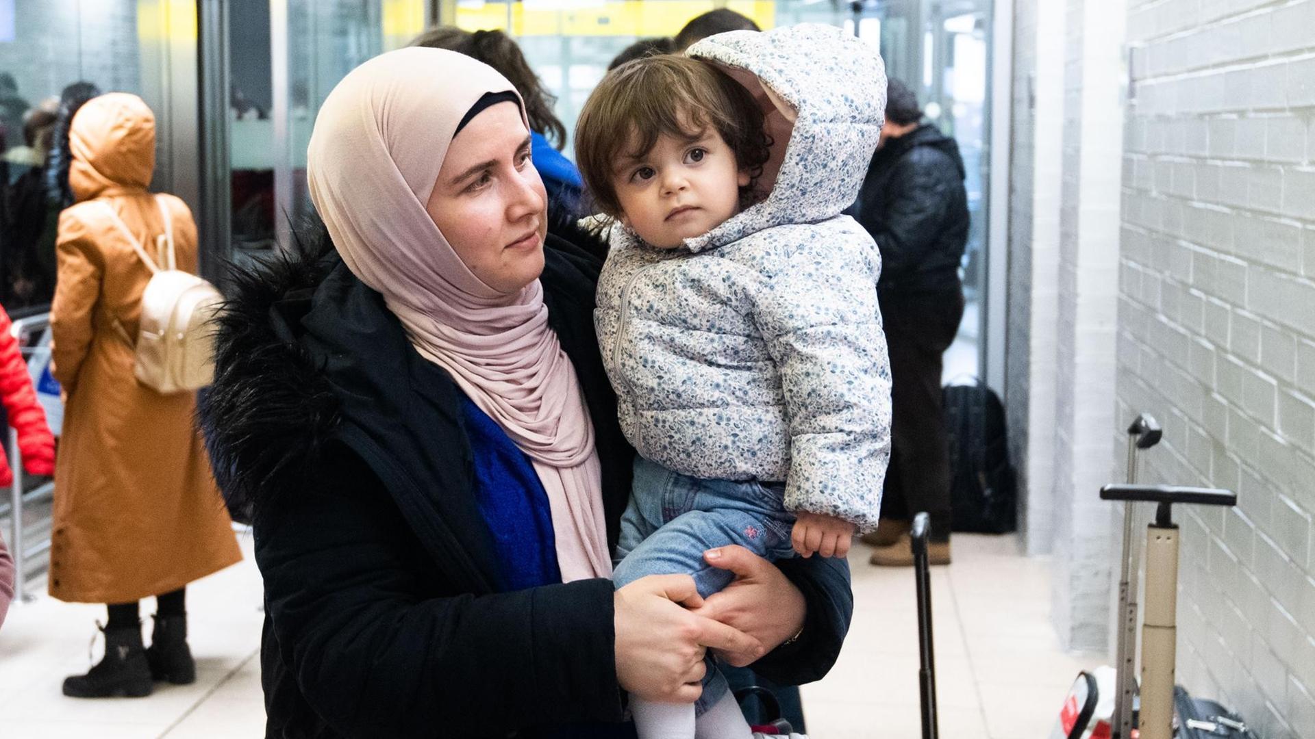 Nach ihrer Ankunft steht eine Frau mit ihrem Kind auf der Arm im Ankunftsbereich vom Flughafen Hannover. Aus der Türkei sind knapp 250 Flüchtlinge am Flughafen Hannover ankommen. Nach ihrer Ankunft steht eine Frau mit ihrem Kind auf der Arm im Ankunftsbereich vom Flughafen Hannover. Aus der Türkei sind knapp 250 Flüchtlinge am Flughafen Hannover ankommen.