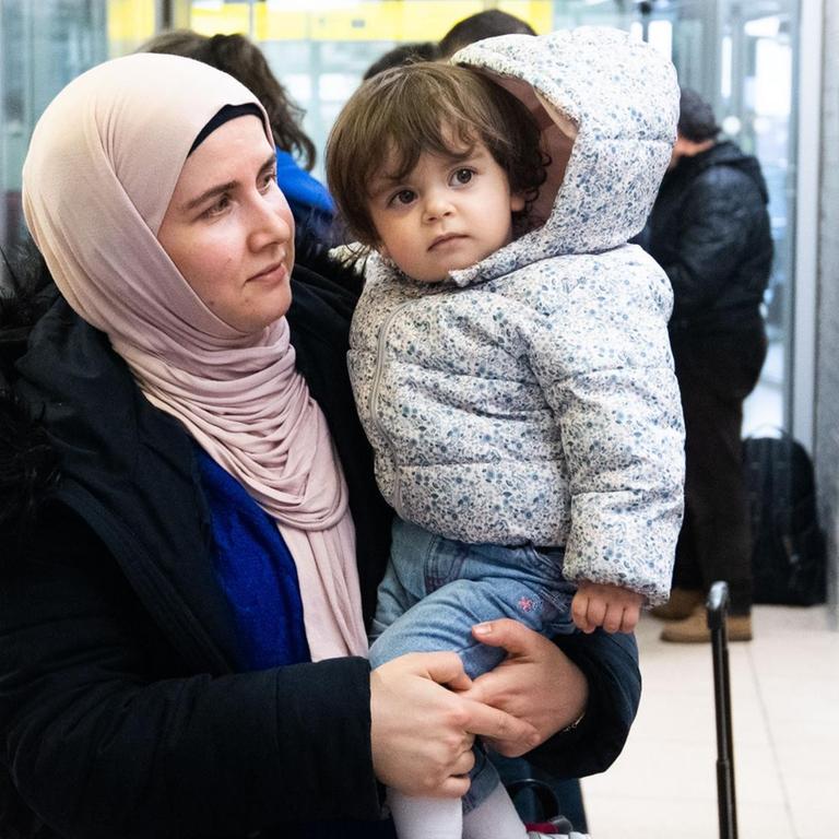 Nach ihrer Ankunft steht eine Frau mit ihrem Kind auf der Arm im Ankunftsbereich vom Flughafen Hannover. Aus der Türkei sind knapp 250 Flüchtlinge am Flughafen Hannover ankommen.