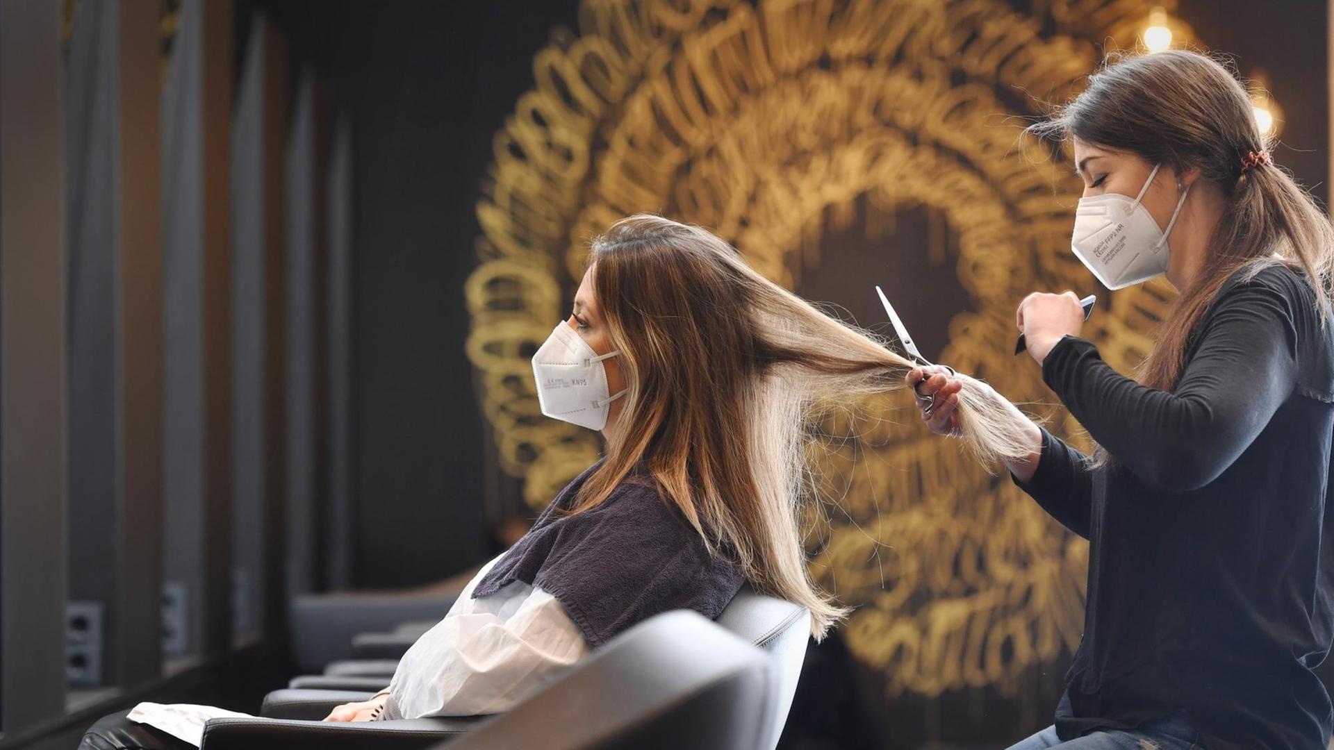 Eine Friseurin schneidet einer Kundin die Haare. Eine Friseurin schneidet einer Kundin die Haare.