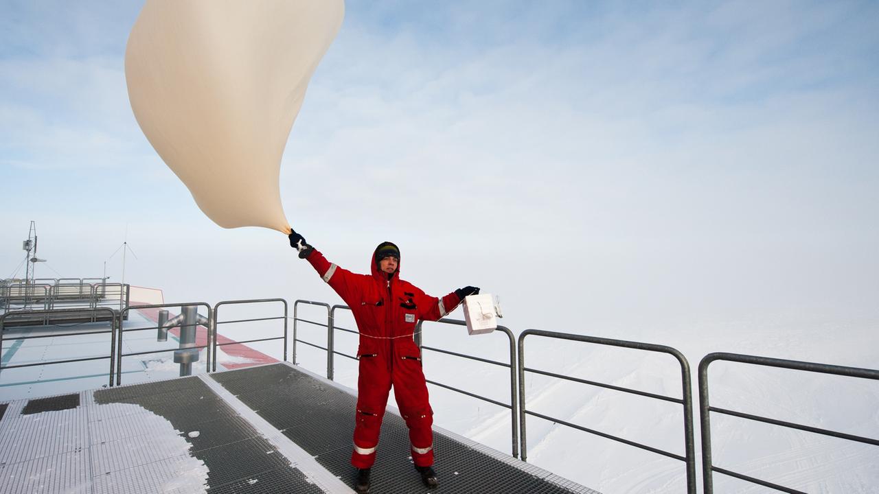 Ein Meteorologe lässt bei windigem Wetter in der Antarktis eine Ozonsonde zur Messung der Ozonkonzentration in der Atmosphäre steigen