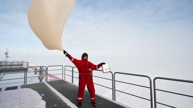 Ein Meteorologe lässt bei windigem Wetter in der Antarktis eine Ozonsonde steigen.