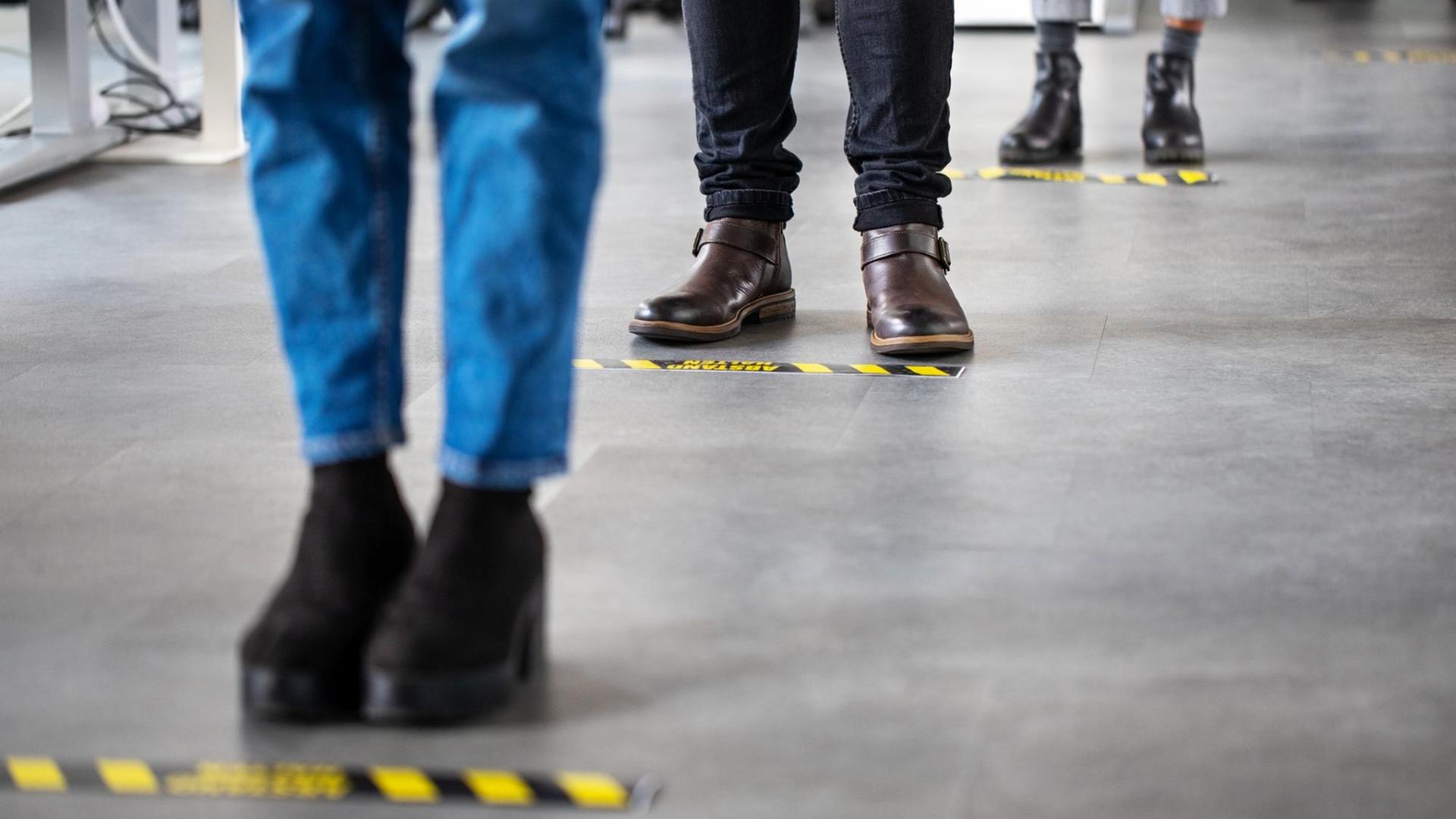 Auf dem Boden ist das Klebeband im Abstand von 1,5 Meter angebracht. Pro Markierung wartet eine Person. Auf dem Boden ist das Klebeband im Abstand von 1,5 Meter angebracht. Pro Markierung wartet eine Person.