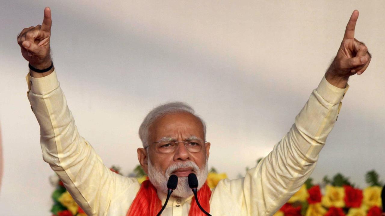 Narendra Modi steht am Mikrofon und hebt die Arme adressierend in die Luft. Narendra Modi steht am Mikrofon und hebt die Arme adressierend in die Luft.