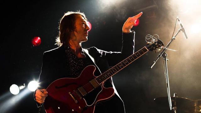 Der Sänger und Gitarrist Jochen Distelmeyer bei einem Auftritt im Berliner Astra Club im Jahr 2014. Er gestikuliert mit einer Hand. Im Hintergrund fahrige Lichter.