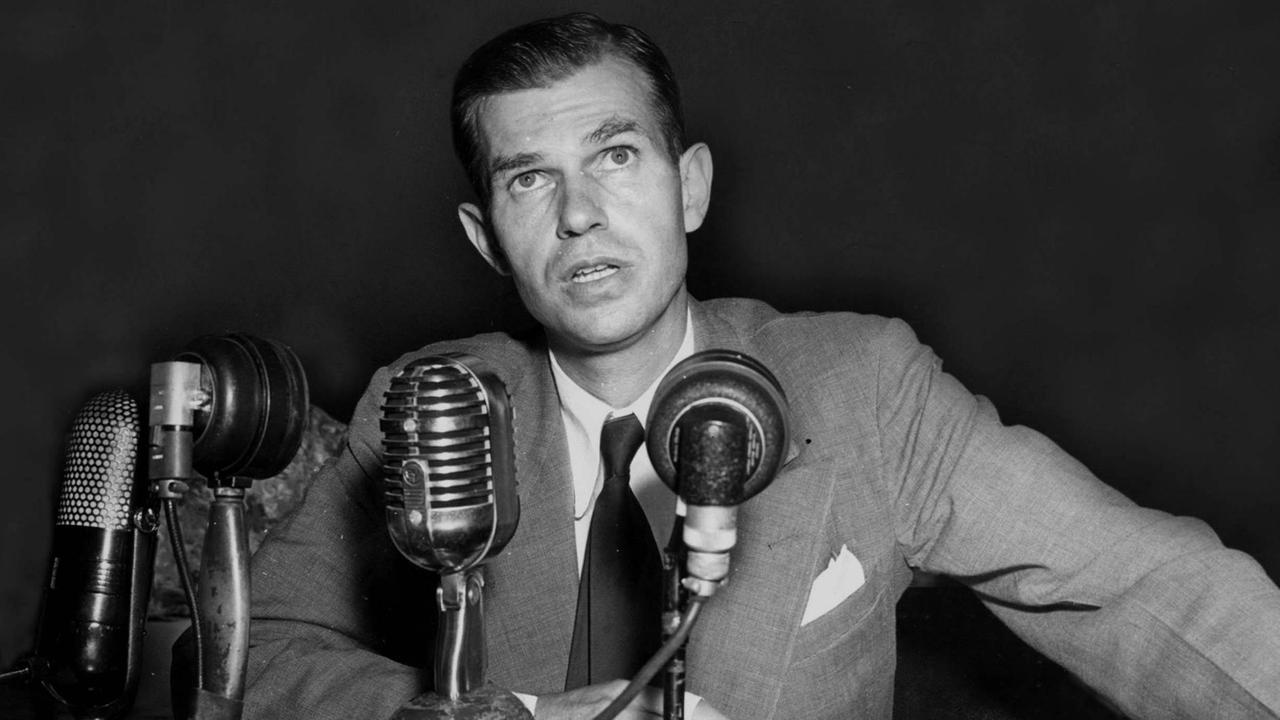 Alger Hiss während einer Anhörung im August 1948, auf der er seine Unschuld bezeugt. Ihm wurde vorgeworfen, für die Sowjetunion zu spionieren. Vor ihm stehen mhere Mikrofone. 