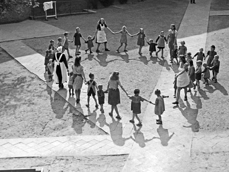 Schwestern tanzen mit den Kindern eines Kinderheims einen Ringeltanz in Frankfurt an der Oder, 1948.