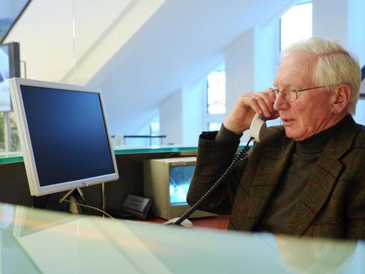 Der Senior Hugo Kleine (76) telefoniert am 22.03.2012 während seiner Arbeit am Empfang einer Behörde in Kiel. Der ehemalige Automobilkaufmann ist seit 2001 im Wechsel mit einem Kollegen für mehrere Wochenstunden am Empfang des Wirtschaftsministeriums in Kiel beschäftigt.