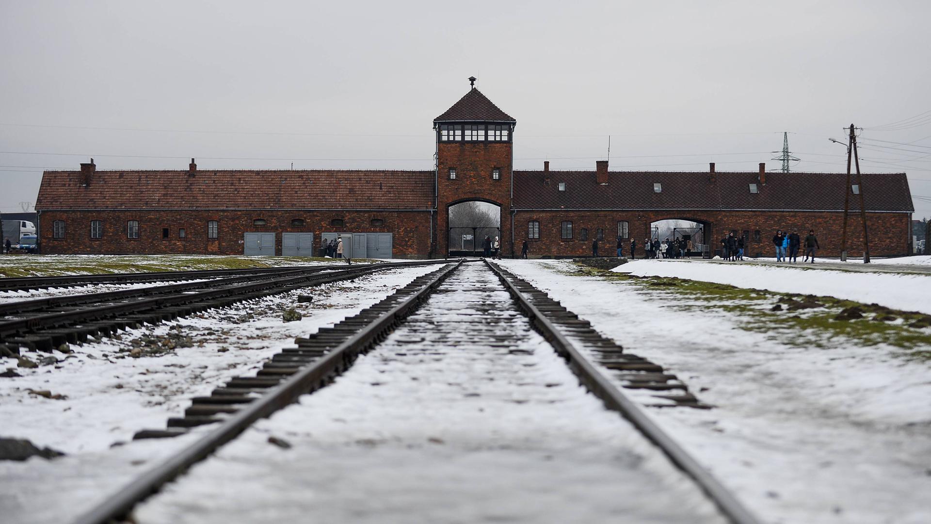 Ein Gleis führt zu einem großen Backsteinbau Ein Gleis führt zu einem großen Backsteinbau