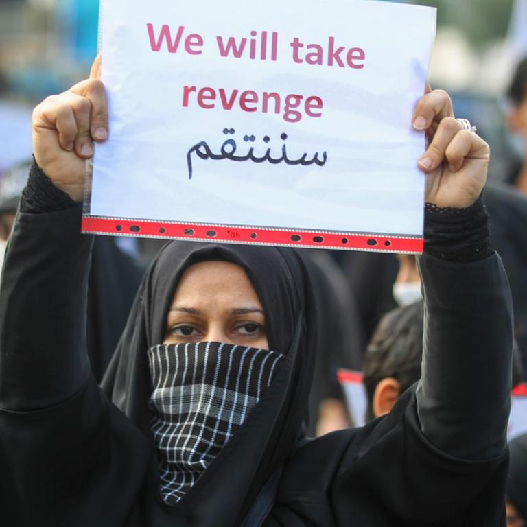 An Iraqi woman holds a placard during the funeral of Iranian military commander Qasem Soleimani, Iraqi paramilitary chief Abu Mahdi al-Muhandis and eight others in Baghdad's district of al-Jadriya, in Baghdad's high-security Green Zone, on January 4, 2020. - Thousands of Iraqis chanting "Death to America" joined the funeral procession for Iranian commander Qassem Soleimani and Iraqi paramilitary chief Abu Mahdi al-Muhandis, both killed in a US air strike. The cortege set off around Kadhimiya, a Shiite pilgrimage district of Baghdad, before heading to the Green Zone government and diplomatic district where a state funeral was to be held attended by top dignitaries. In all, 10 people -- five Iraqis and five Iranians -- were killed in Friday morning's US strike on their motorcade just outside Baghdad airport. (Photo by AHMAD AL-RUBAYE / AFP)