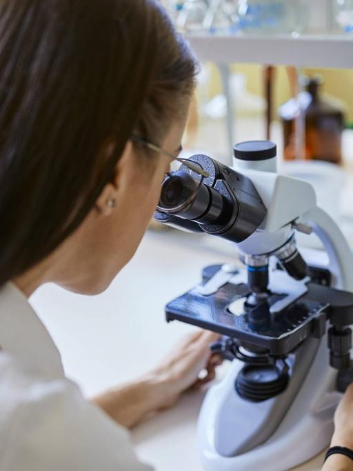 Young woman using microscope in laboratory model released Symbolfoto property released PUBLICATIONxINxGERxSUIxAUTxHUNxONLY ZEDF01018