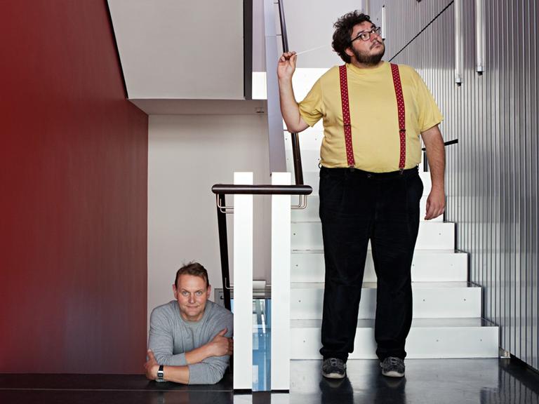 Devid Striesow und Axel Ranisch stehen im Treppenhaus von Deutschlandfunk Kultur.