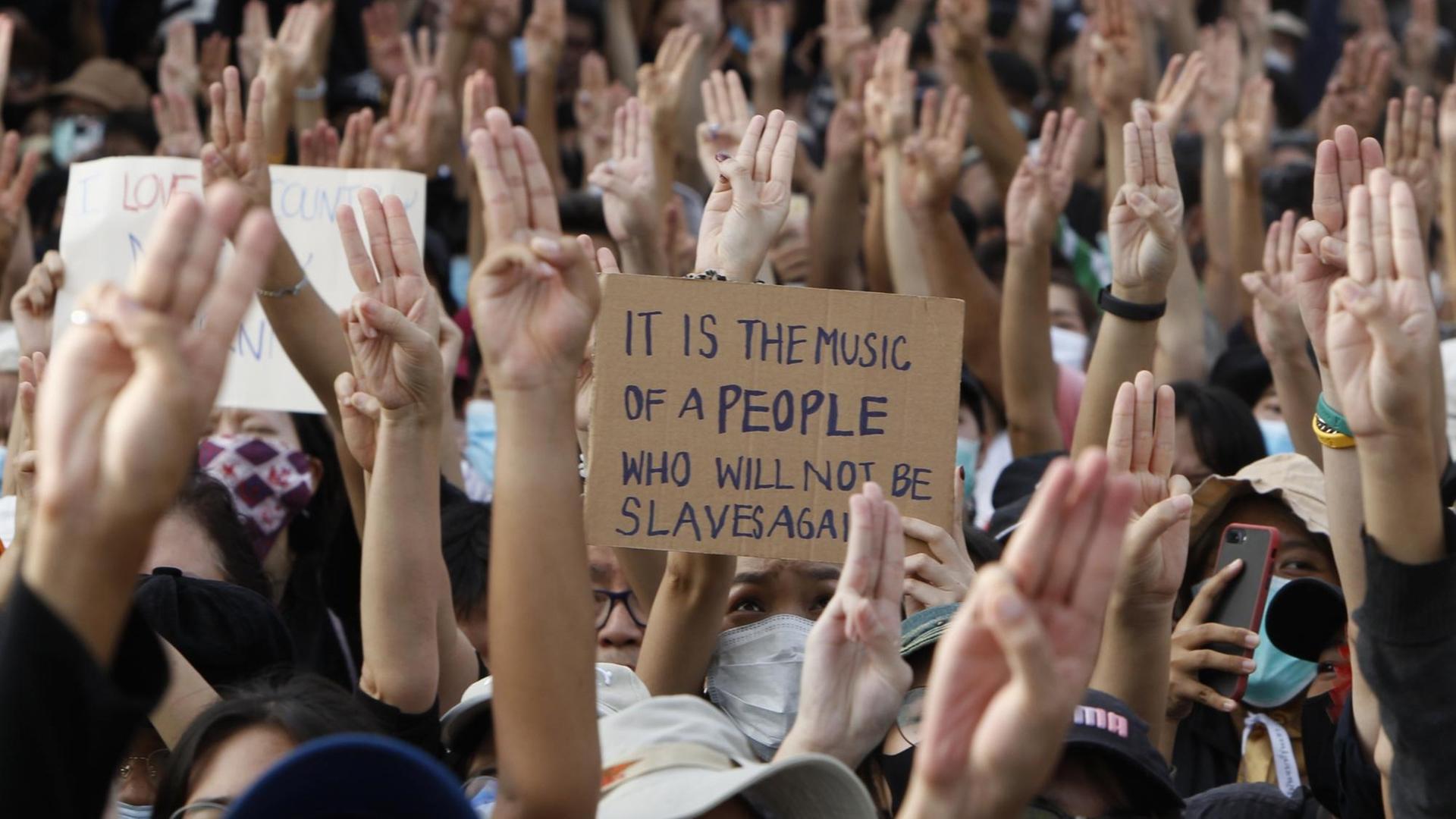 Proteste in Bangkok, Thailand. Die Menschen halten die Hände mit dem Drei-Finger-Gruß in die Luft, 16. August 2020.