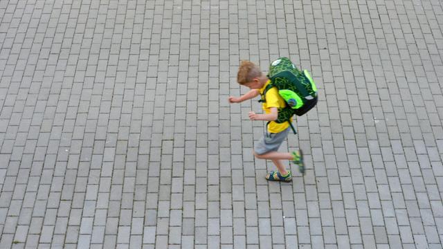 Ein kleiner Junge saust in Berlin mit seinem Schulranzen auf dem Rücken in die Schule. Foto: Volkmar Heinz/dpa-Zentralbild/ZB | Verwendung weltweit