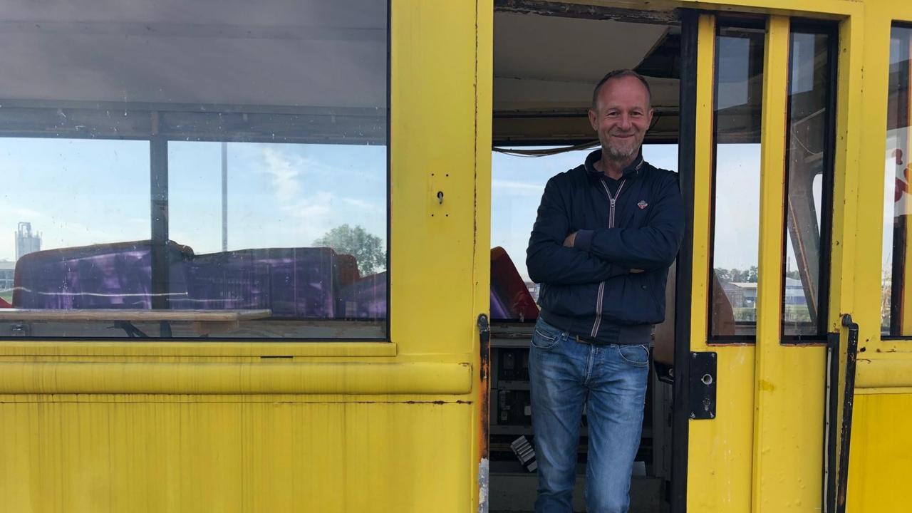 Michael Scheer lehnt in der Tür eines gelben Eisenbahnwaggons.