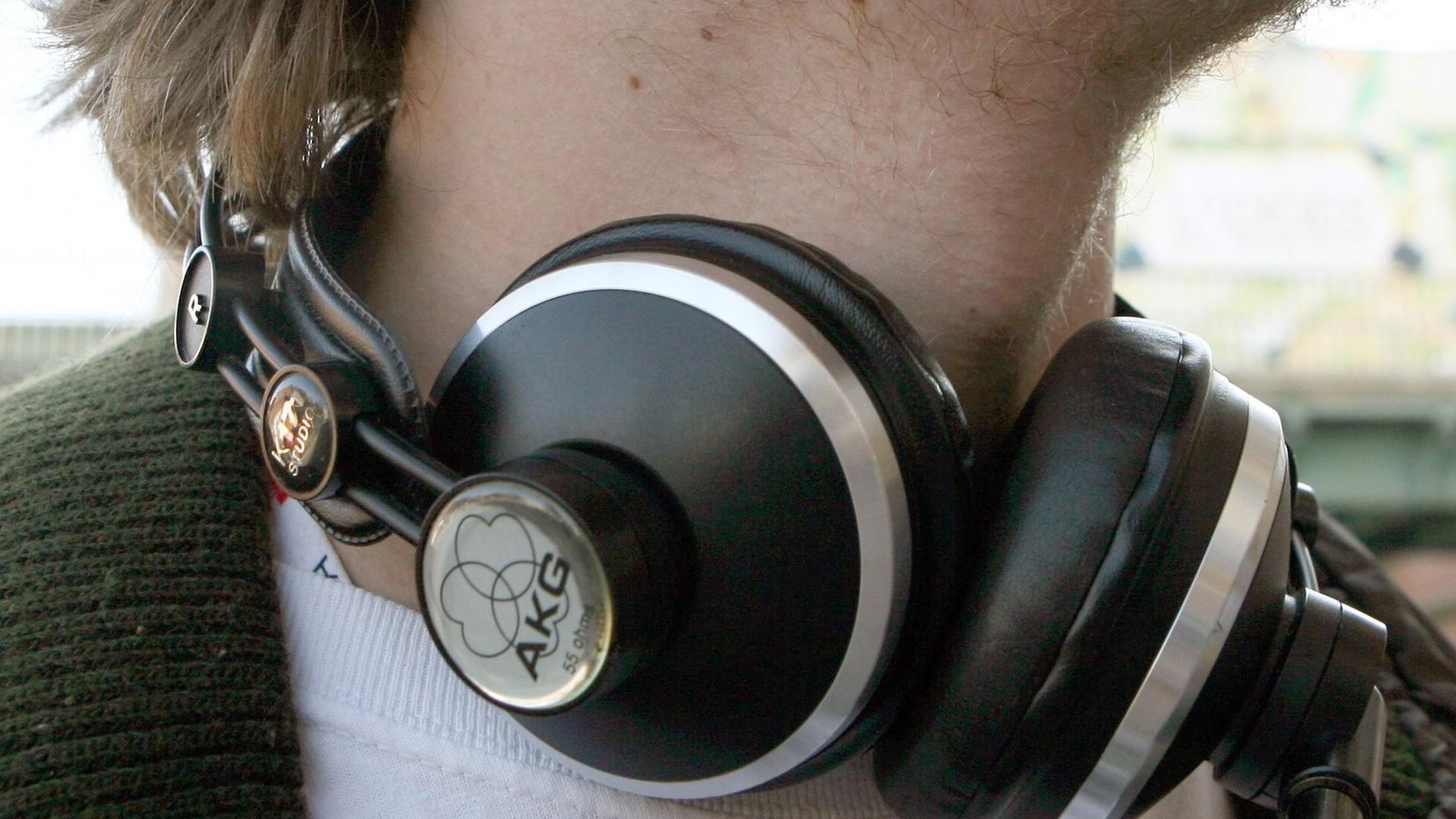 Ein junger Mann trägt große Kopfhörer um den Hals.