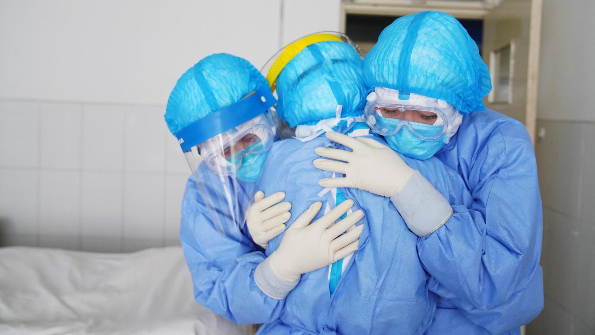 Drei Krankenpflegerinnen umarmen sich.