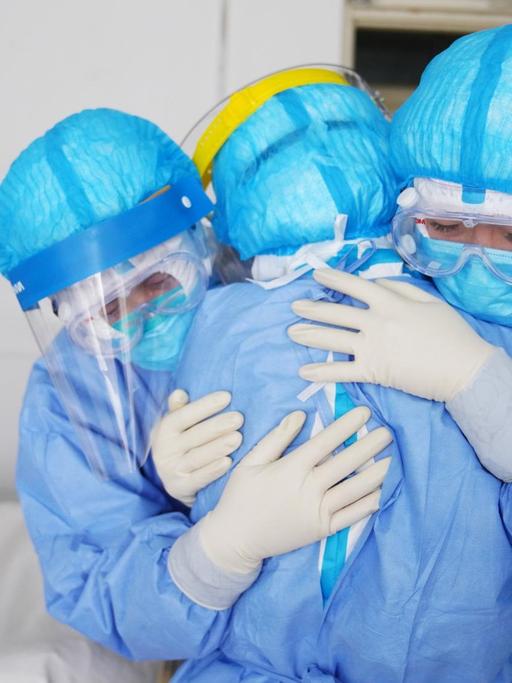 Drei Krankenpflegerinnen umarmen sich.