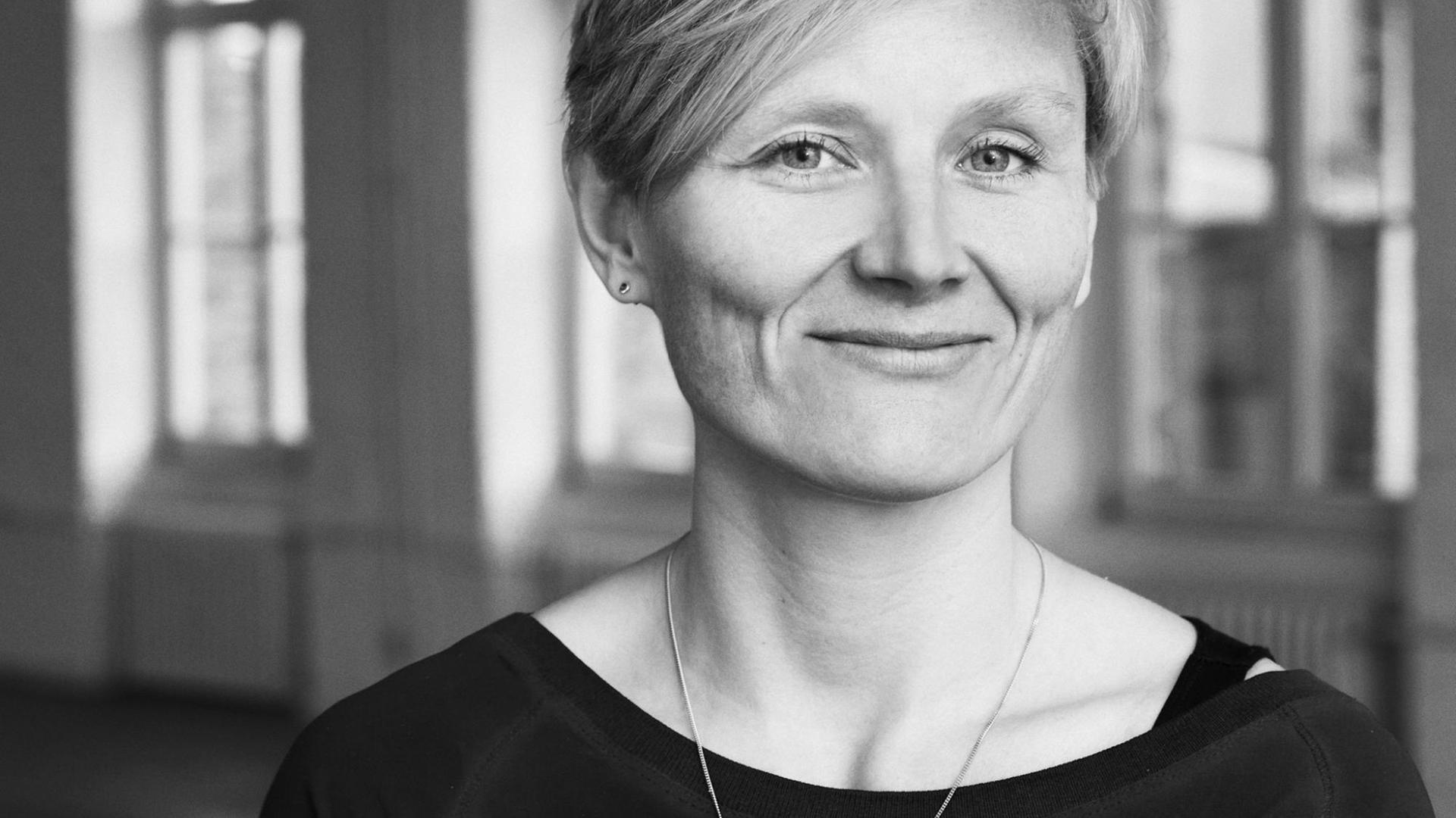 Eine Frau mit kurzen blonden Haaren blickt frontal und lächelnd in die Kamera. Eine Frau mit kurzen blonden Haaren blickt frontal und lächelnd in die Kamera.